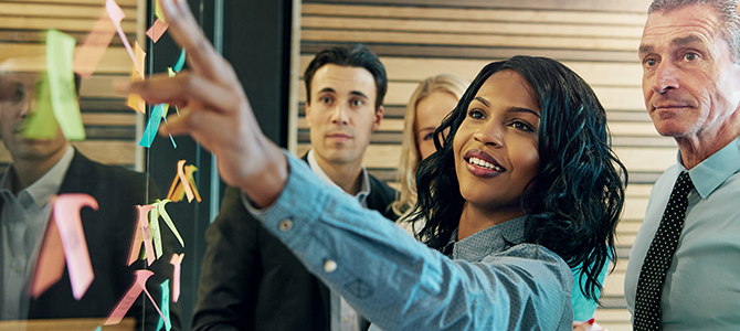 A woman points at something on a board during a meeting.